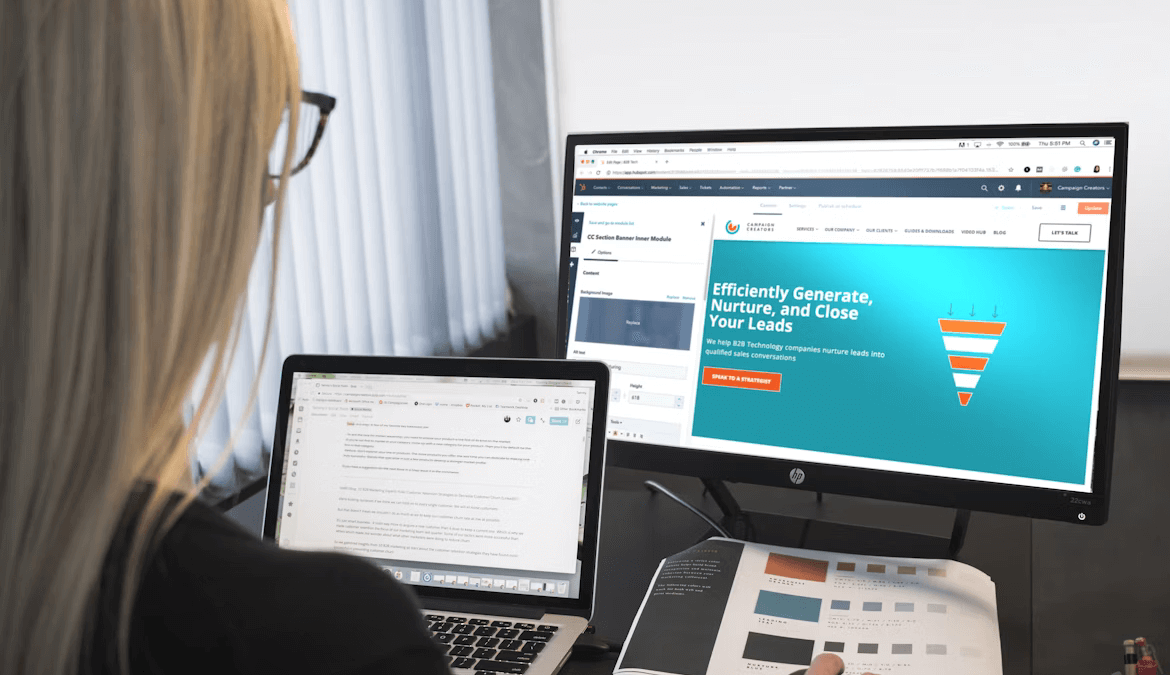 Image of a web designer working in front of a desktop and laptop