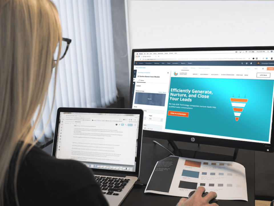 Image of a web designer working in front of a desktop and laptop